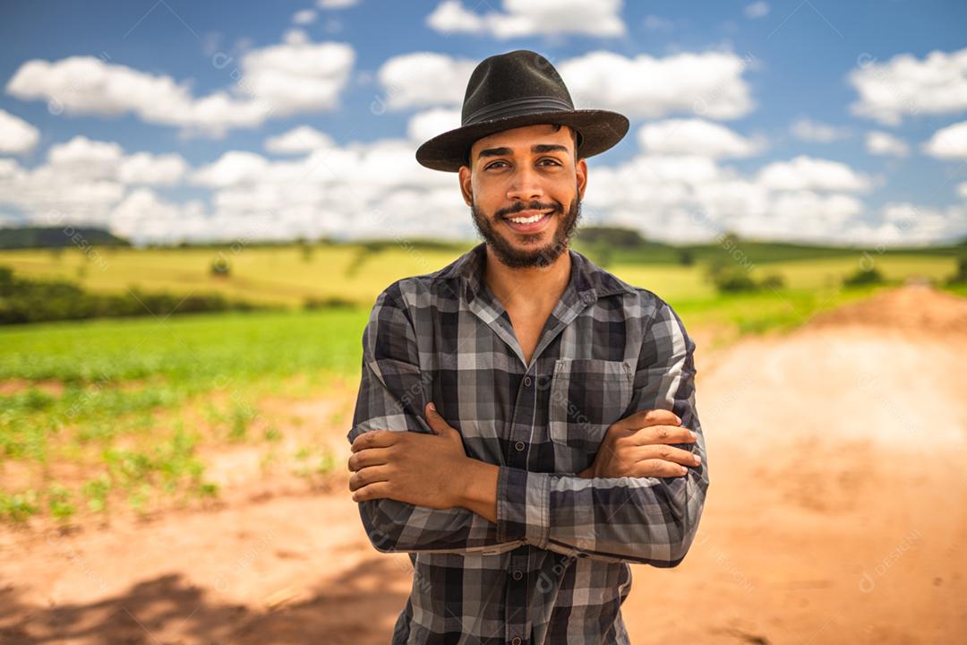 Retrato de um orgulhoso agricultor latino-americano em pé com os braços cruzados, olhando para a câmera.
