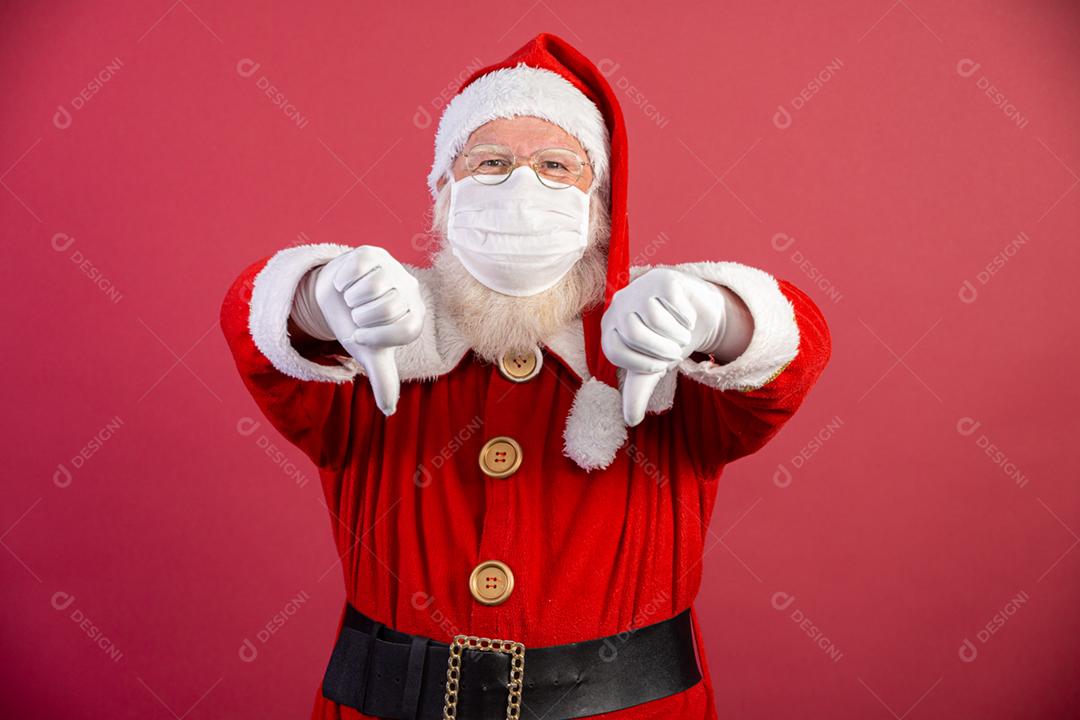 Verdadeiro Papai Noel com fundo vermelho, usando uma máscara protetora, óculos e chapéu. Natal com distanciamento social. Covid-19