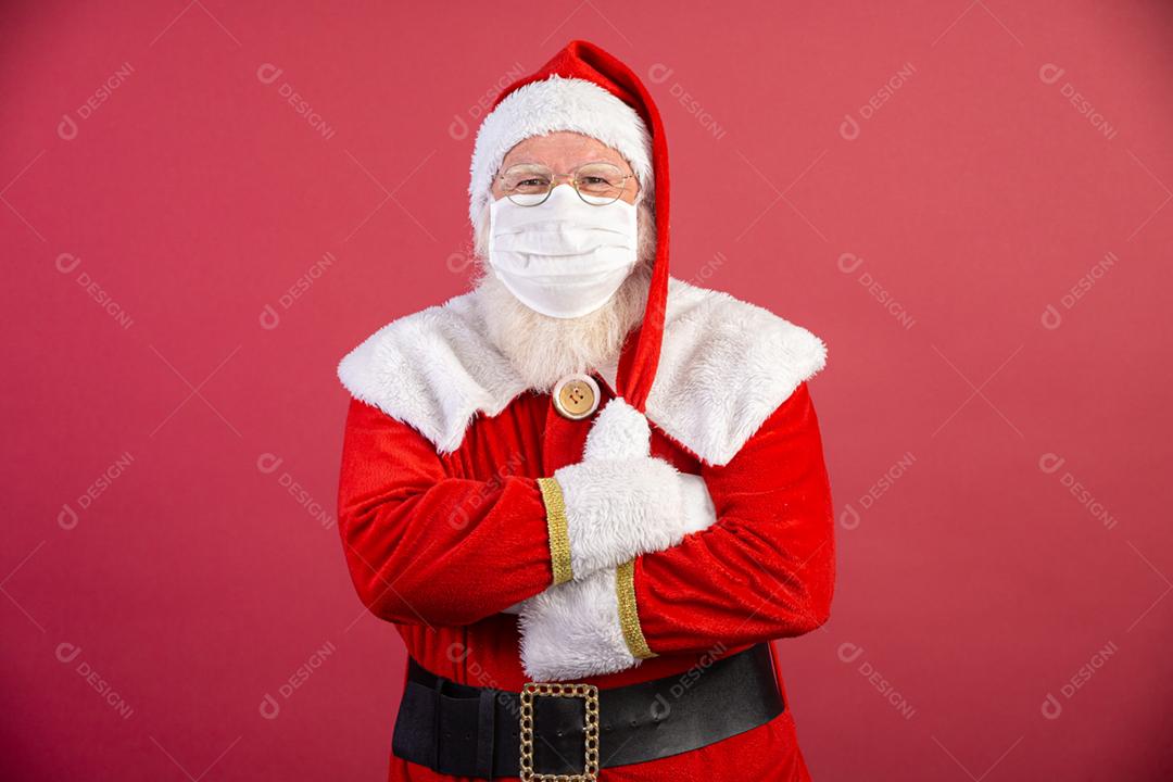 Verdadeiro Papai Noel com fundo vermelho, usando uma máscara protetora, óculos e chapéu. Natal com distanciamento social. Covid-19