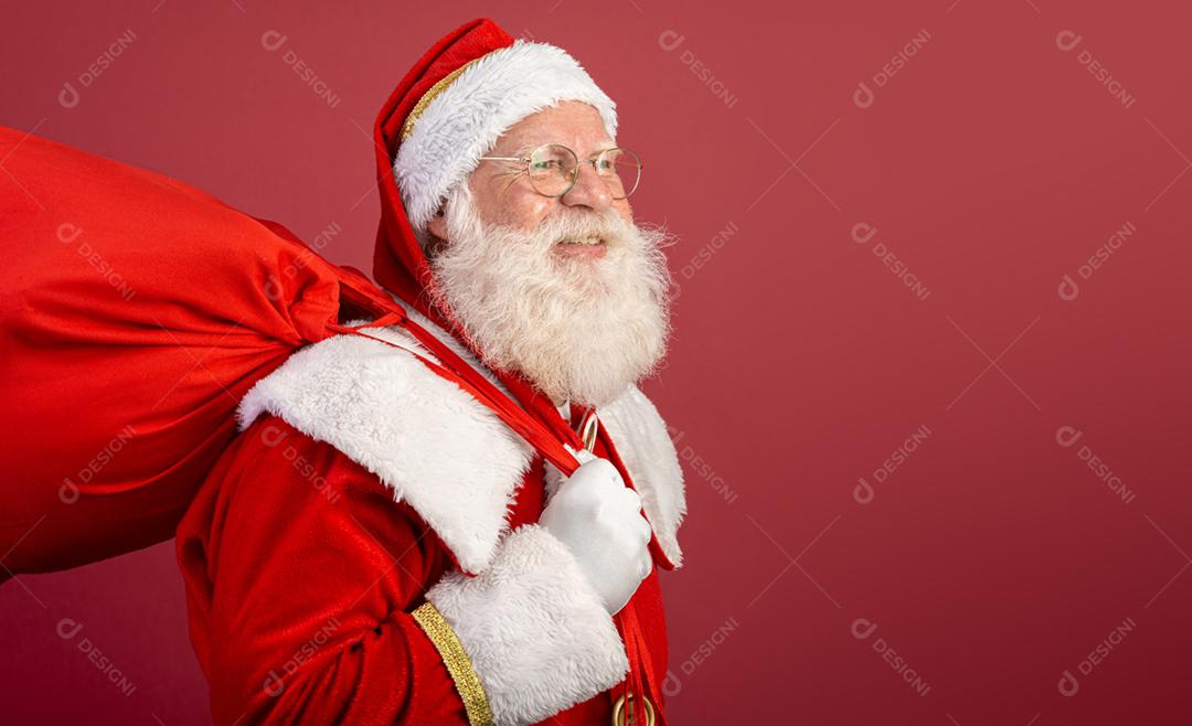 Verdadeiro Papai Noel com um fundo vermelho, usando óculos, luvas e um chapéu olhando de lado.