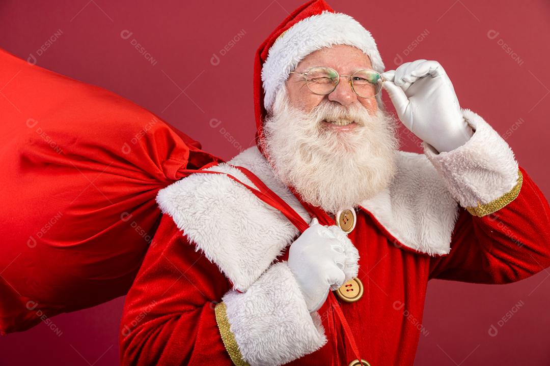 Papai Noel olhando para a câmera. O Natal está chegando. Feliz Natal. Papai Noel está assistindo. Segurando os óculos.