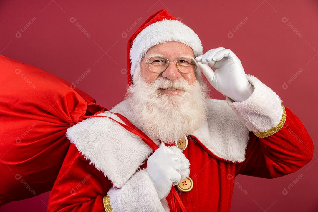 Papai Noel olhando para a câmera. O Natal está chegando. Feliz Natal. Papai Noel está assistindo. Segurando os óculos.