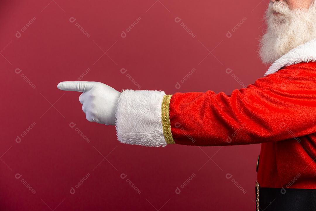 Foto da mão enluvada do Papai Noel no gesto de apontar. Papai Noel apontando os dedos sobre vermelho