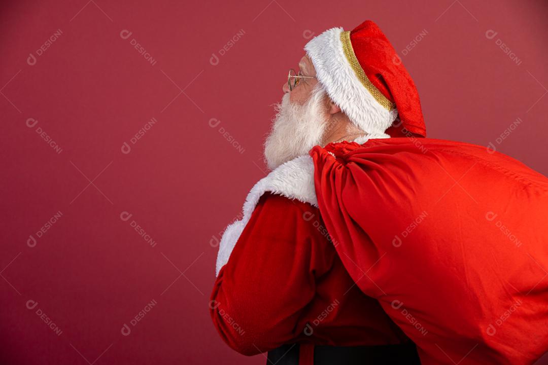 Papai Noel puxando um enorme saco de presentes em fundo vermelho