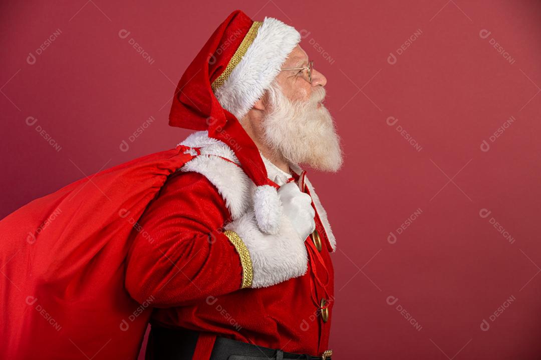 Papai Noel puxando um enorme saco de presentes em fundo vermelho
