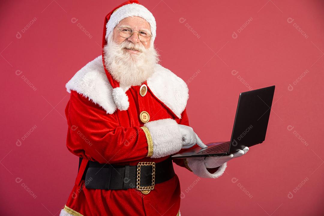 Papai Noel usando um laptop em fundo vermelho.