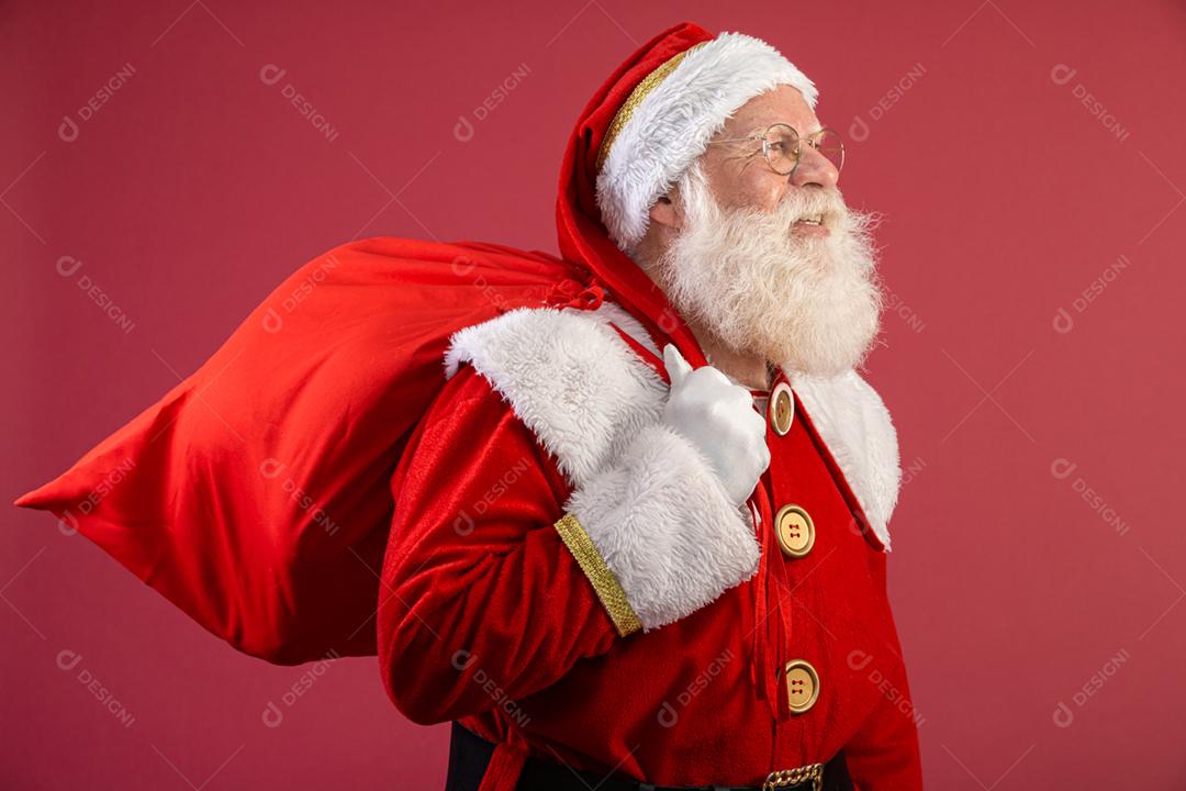 Papai Noel puxando um enorme saco de presentes em fundo vermelhovArte da bandeira.