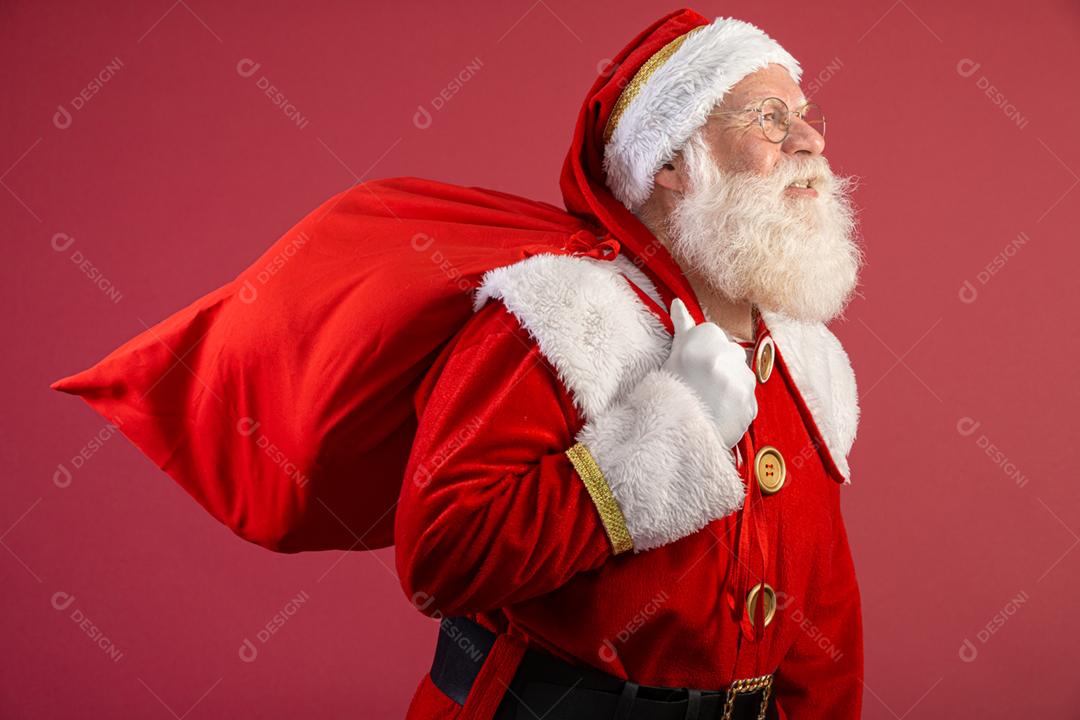 Papai Noel puxando um enorme saco de presentes em fundo vermelhovArte da bandeira.