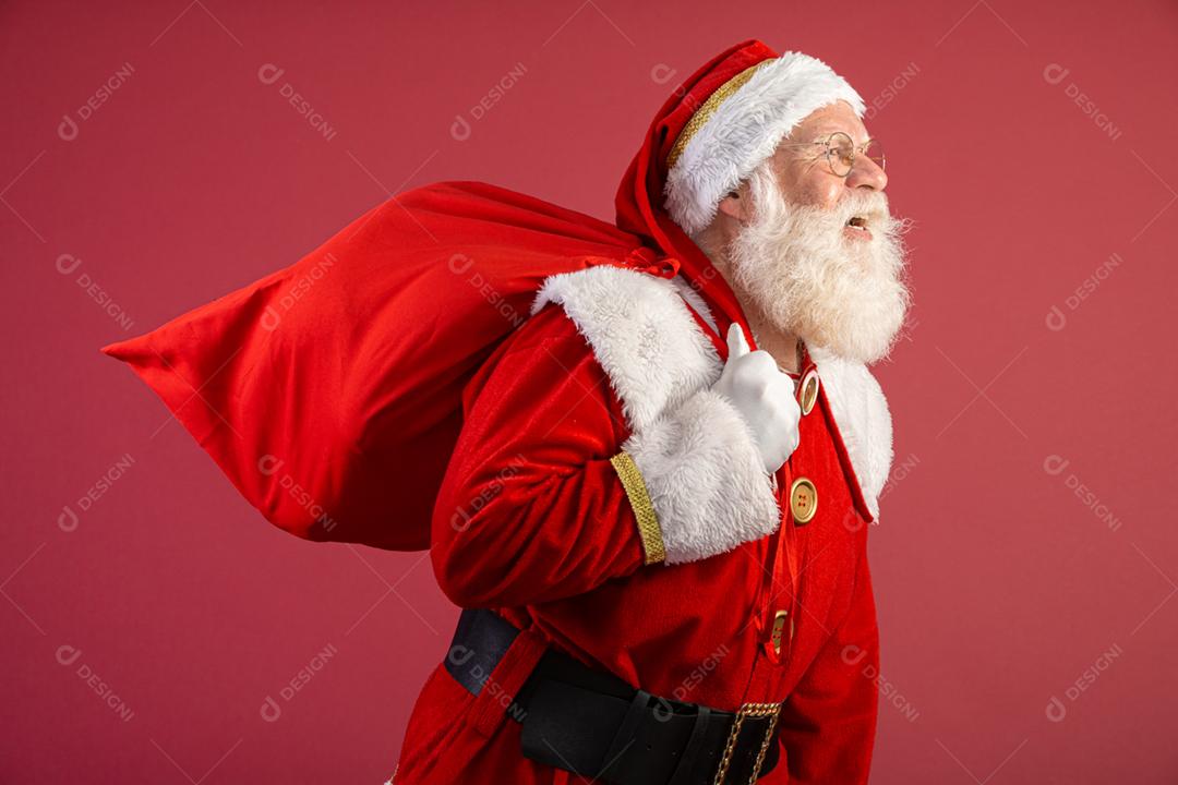 Papai Noel puxando um enorme saco de presentes em fundo vermelhovArte da bandeira.