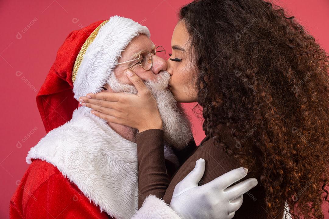 Mulher de cabelo encaracolado beijando Papai Noel.