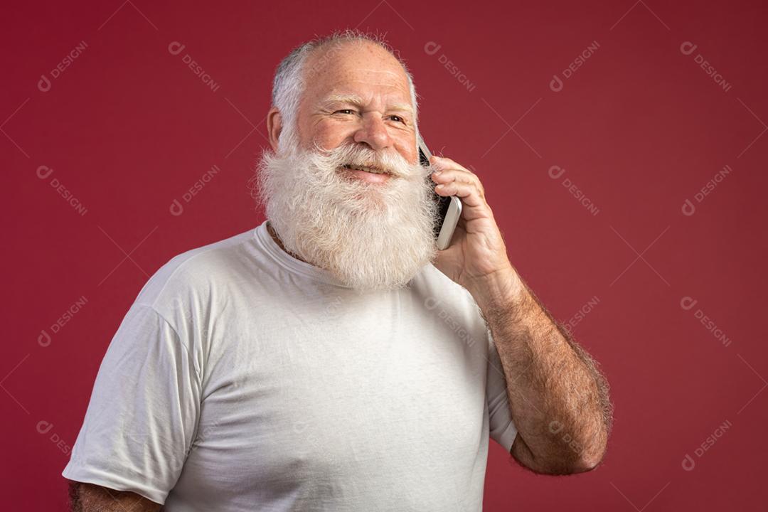 Homem barbudo idoso sorridente usando smartphone em fundo vermelho. Homem sênior usando conexão de internete