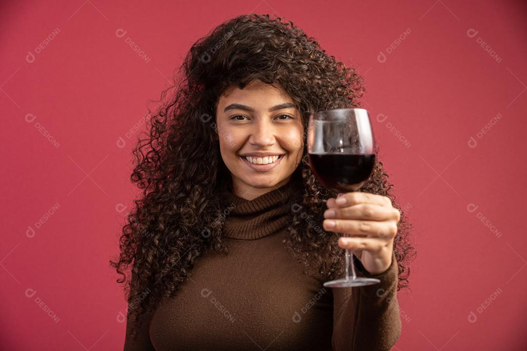 Mulher elegante bebendo vinho tinto sobre fundo vermelho. jovem brasileira.