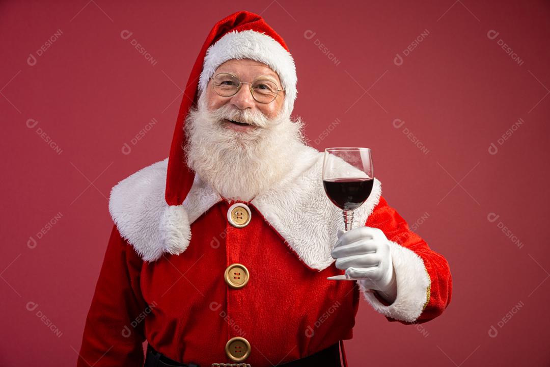 Noel segurando um copo de vinho na mão. Papai Noel sobre um fundo vermelho. Bebida tradicional de fim de ano. Promoção de Natal de vinho.