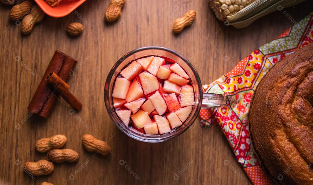 Vinho quente do Brasil com pedaços de maçã, típico da Festa Junina. Comida tradicional do Brasil, o doce da Festa Junina. Fundo de madeira rústico