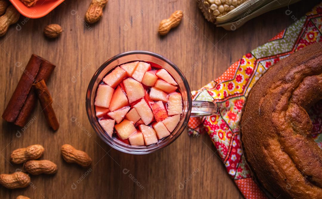 Vinho quente do Brasil com pedaços de maçã, típico da Festa Junina. Comida tradicional do Brasil, o doce da Festa Junina. Fundo de madeira rústico