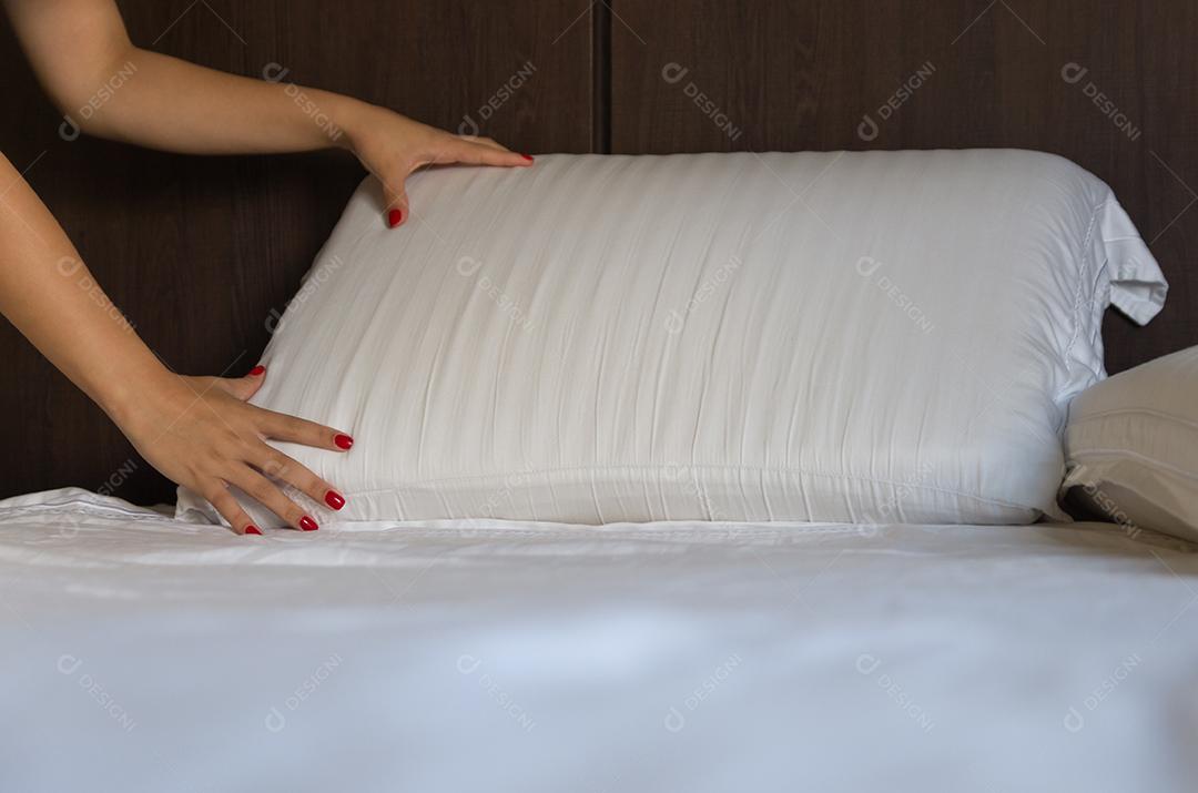 Mulher fazendo a cama. O grande conceito de cama arrumada e organização