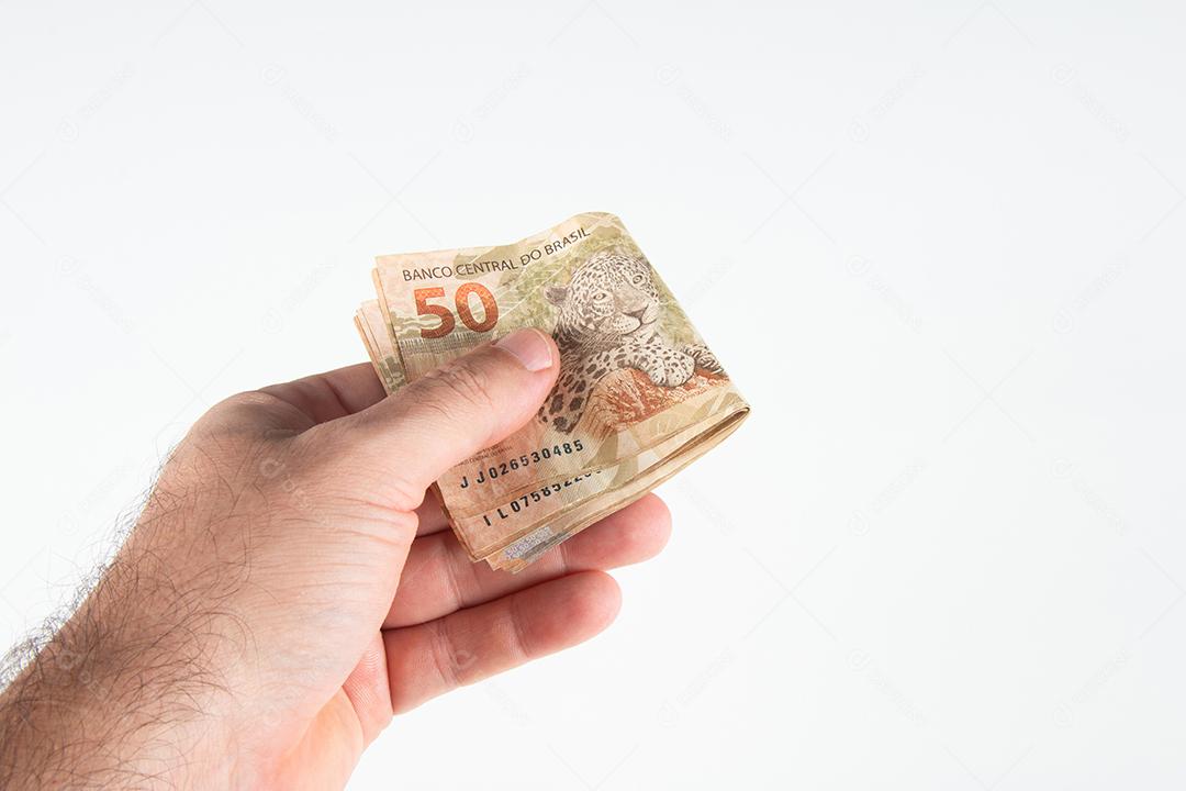 Dinheiro brasileiro. Mão segurando notas de 50 reais. Finanças brasileira