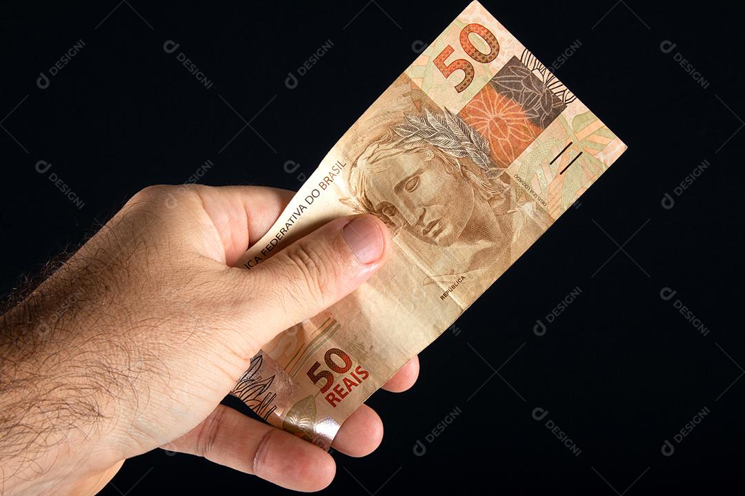 Dinheiro brasileiro. Mão segurando notas de 50 reais. Finanças brasileira