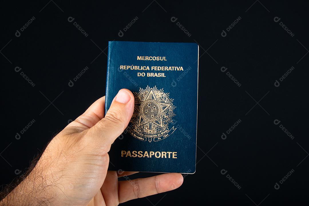 Mão segurando passaporte brasileiro.