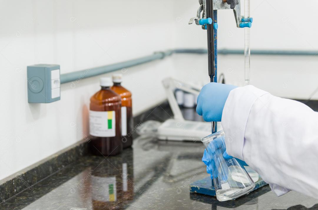 Mãos de mulher realizando teste de titulação no controle de qualidade química.