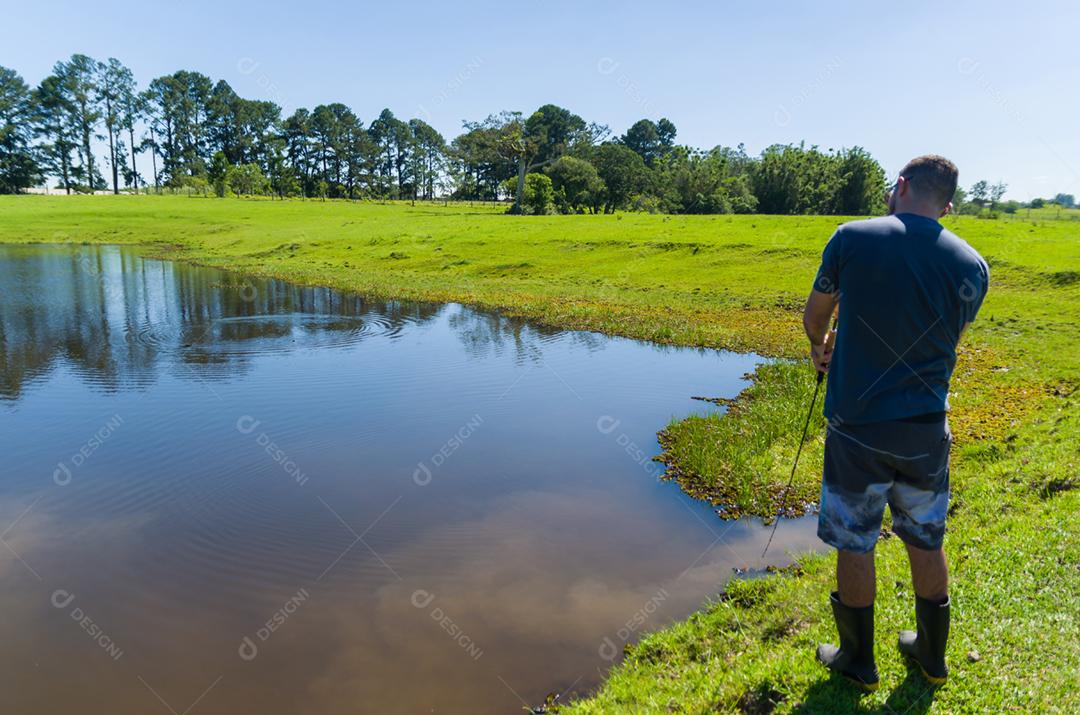 Jovem praticando pesca esportiva em açude, pesca captura e soltura.