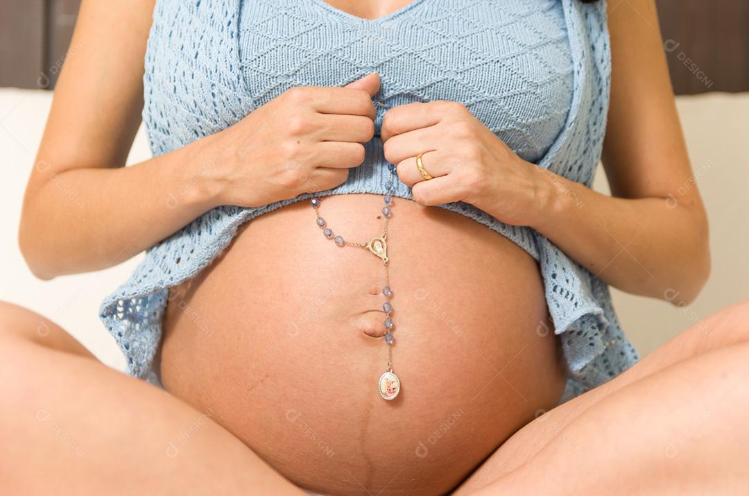 Gravidez, descanso, pessoas e conceito de expectativa - mulher grávida feliz sentada na cama e tocando sua barriga