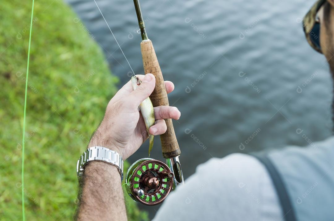 Flyfishing no lago no Brasil, pesca de jovem pescador.