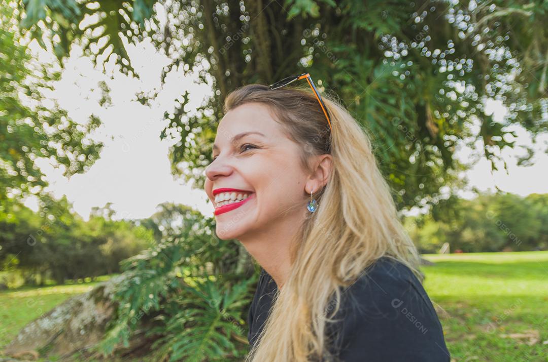 Mulher loira sobre campo verde aproveitando seu piquenique