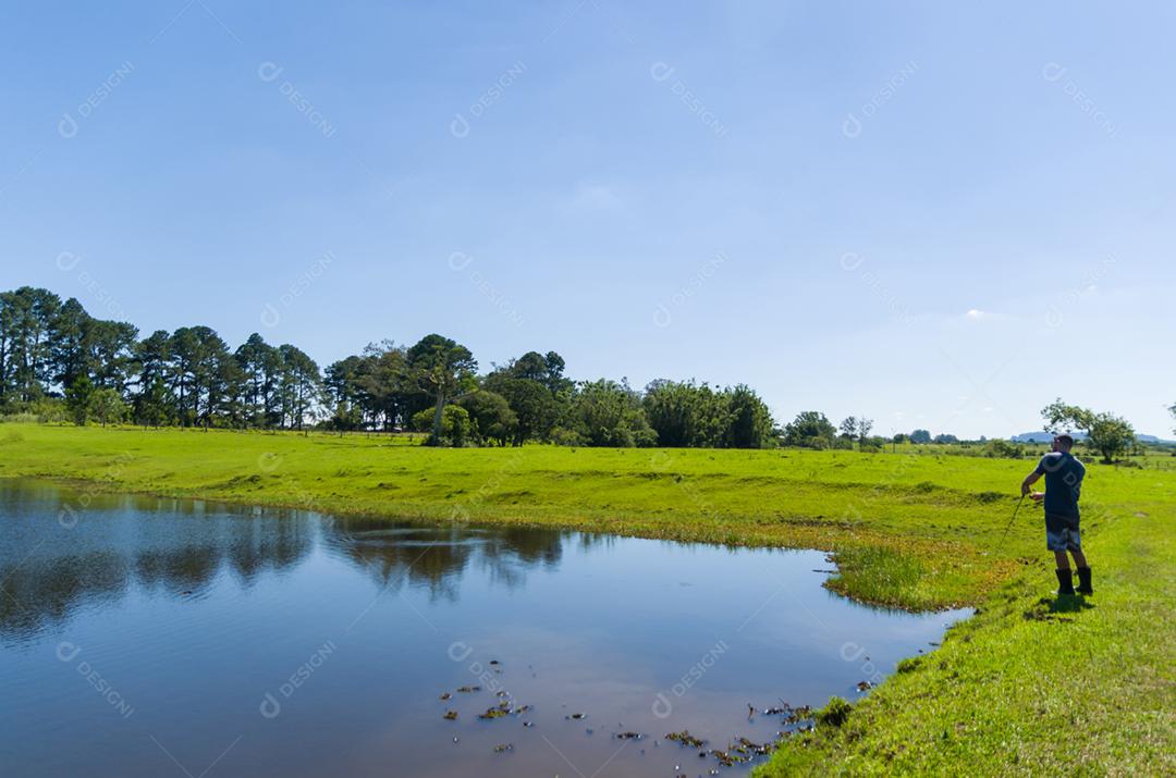 Jovem praticando pesca esportiva em açude, pesca captura e soltura.