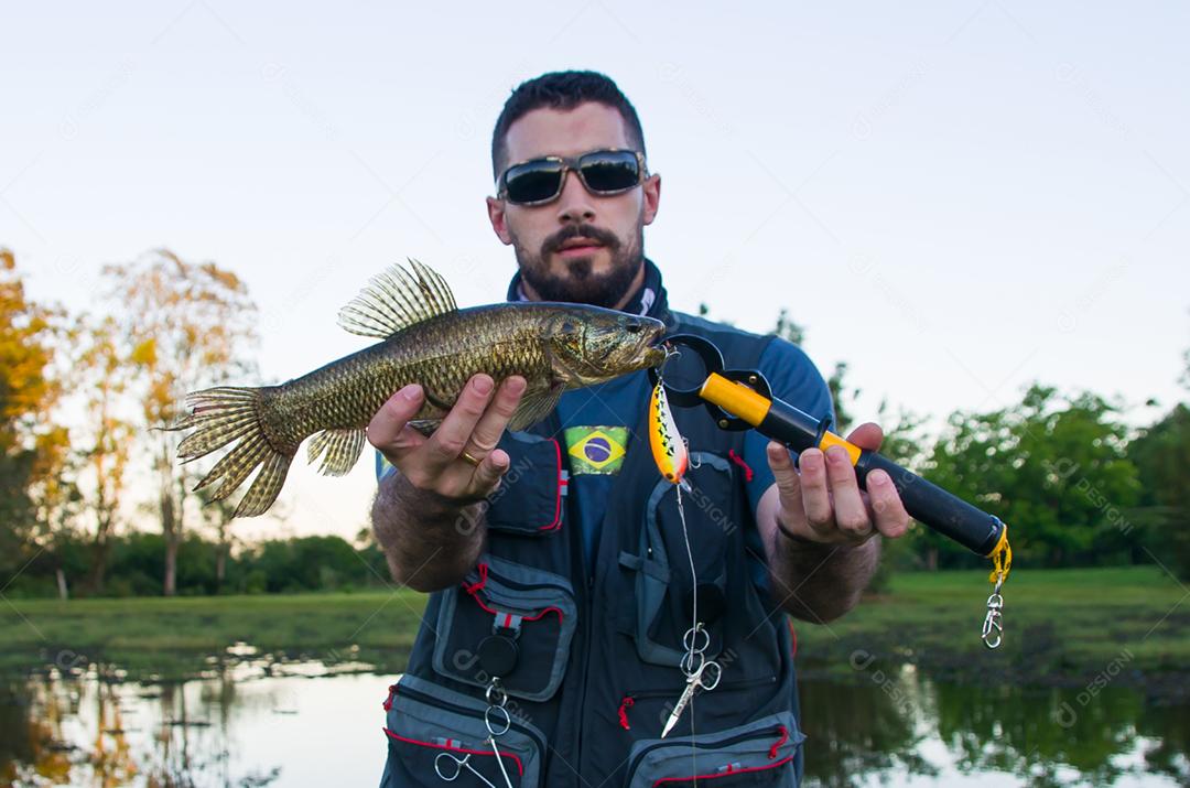 Pescador mostrando peixe que pegou com isca artificial, peixe Traira (Hoplias malabaricus).