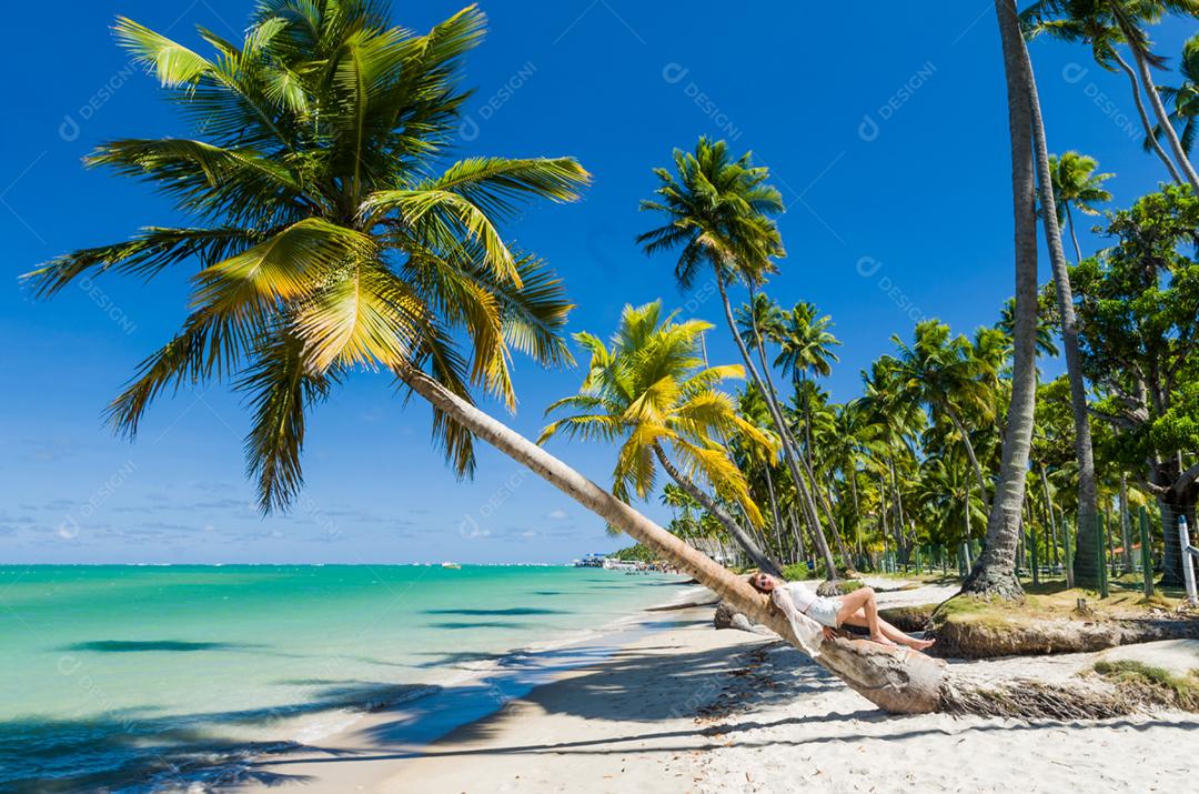 Jovem turista deitada em coqueiro na praia paradisíaca do Brasil, Praia dos Carneiros, Pernambuco, Brasil.