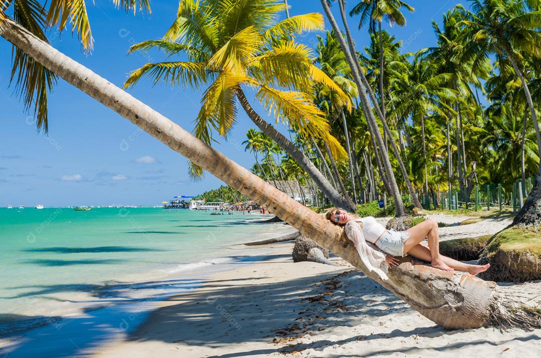 Jovem turista deitada em coqueiro na praia paradisíaca do Brasil, Praia dos Carneiros, Pernambuco, Brasil.