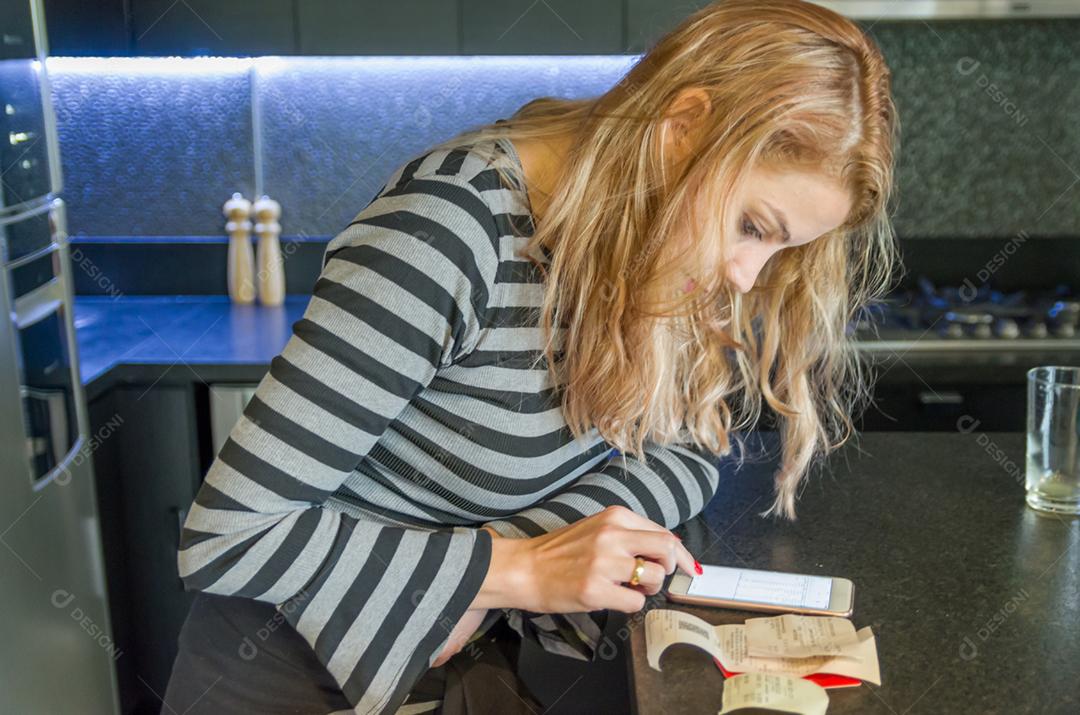 Grande conceito de contas domésticas, mulher calculando as contas com o celular.