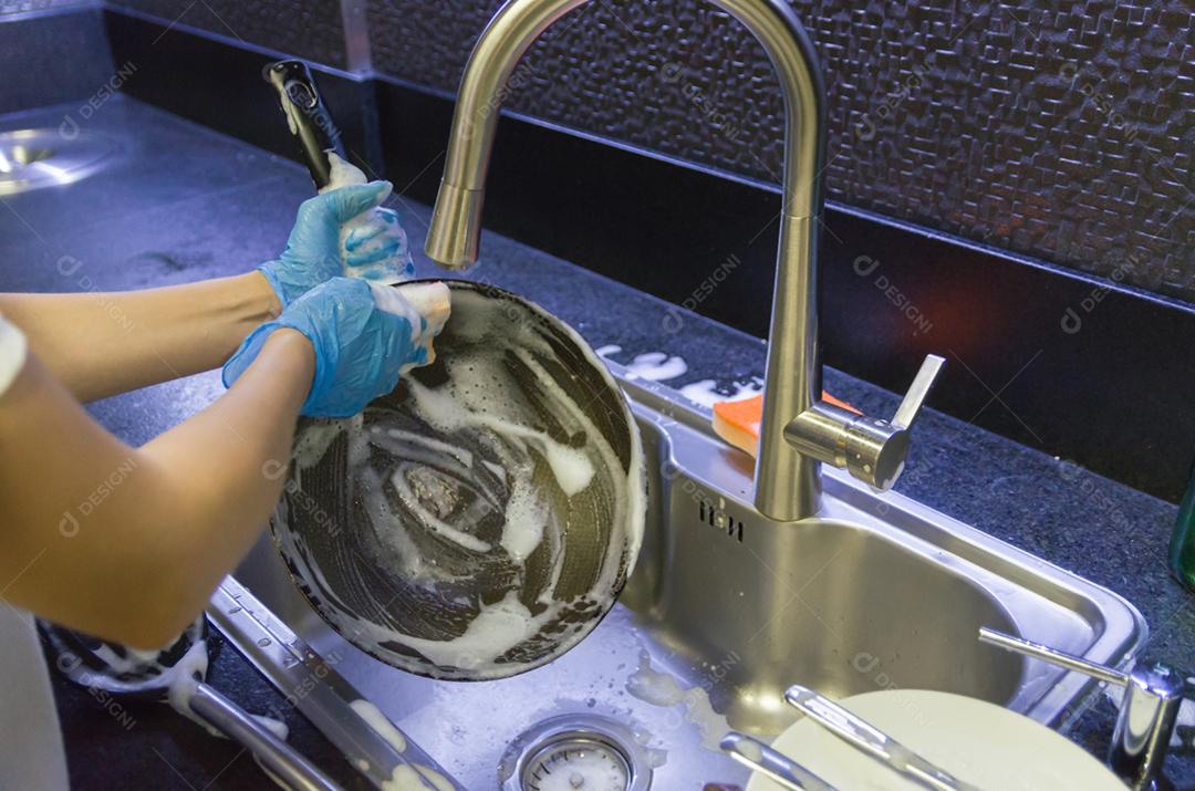 Limpando a louça, panela na pia.