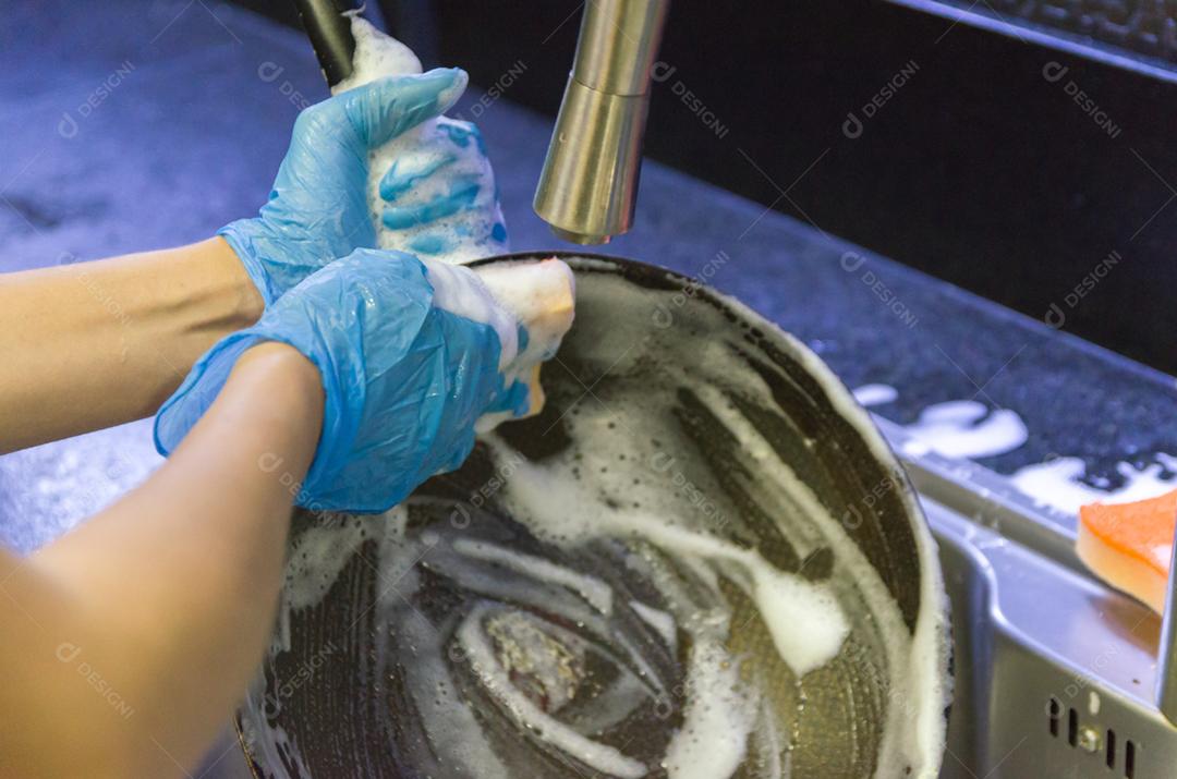 Limpando a louça, panela na pia.