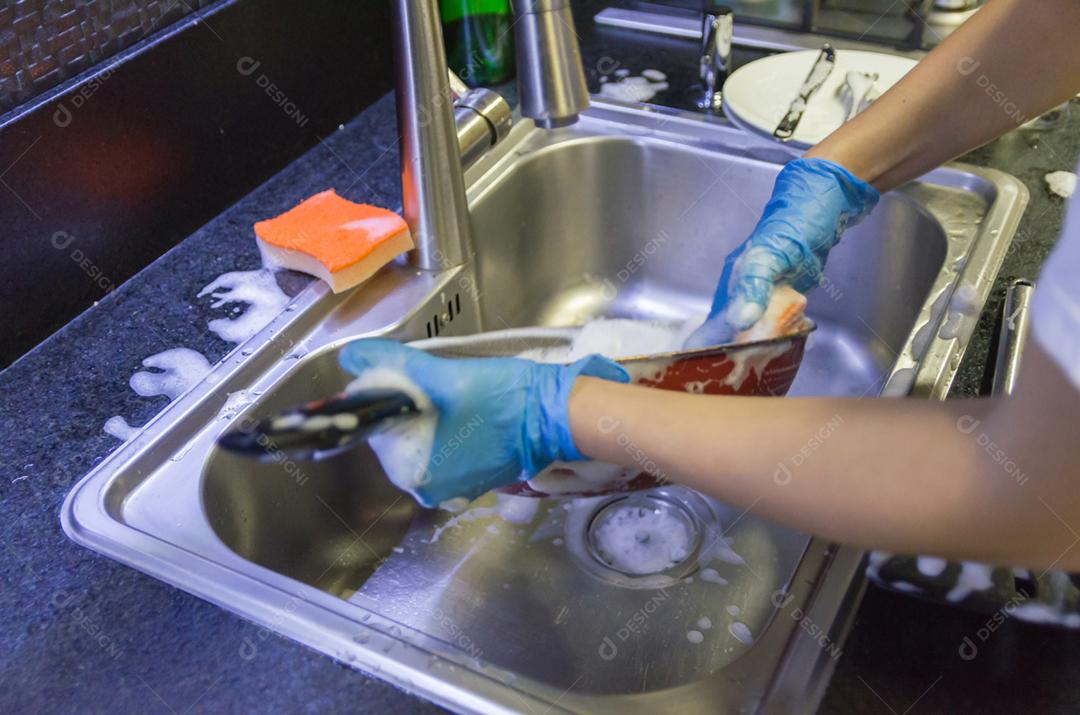 Limpando a louça, panela na pia.