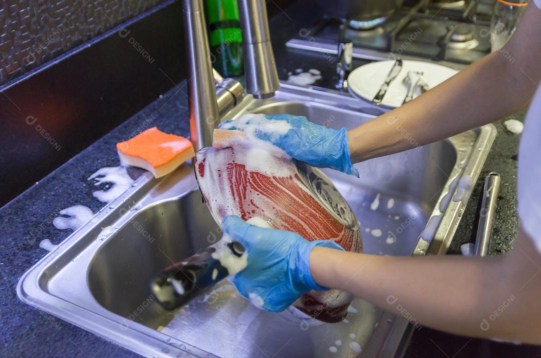 Limpando a louça, panela na pia.