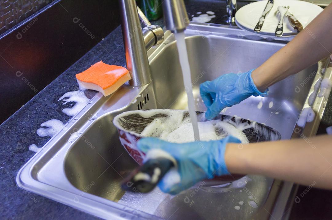Limpando a louça, panela na pia.