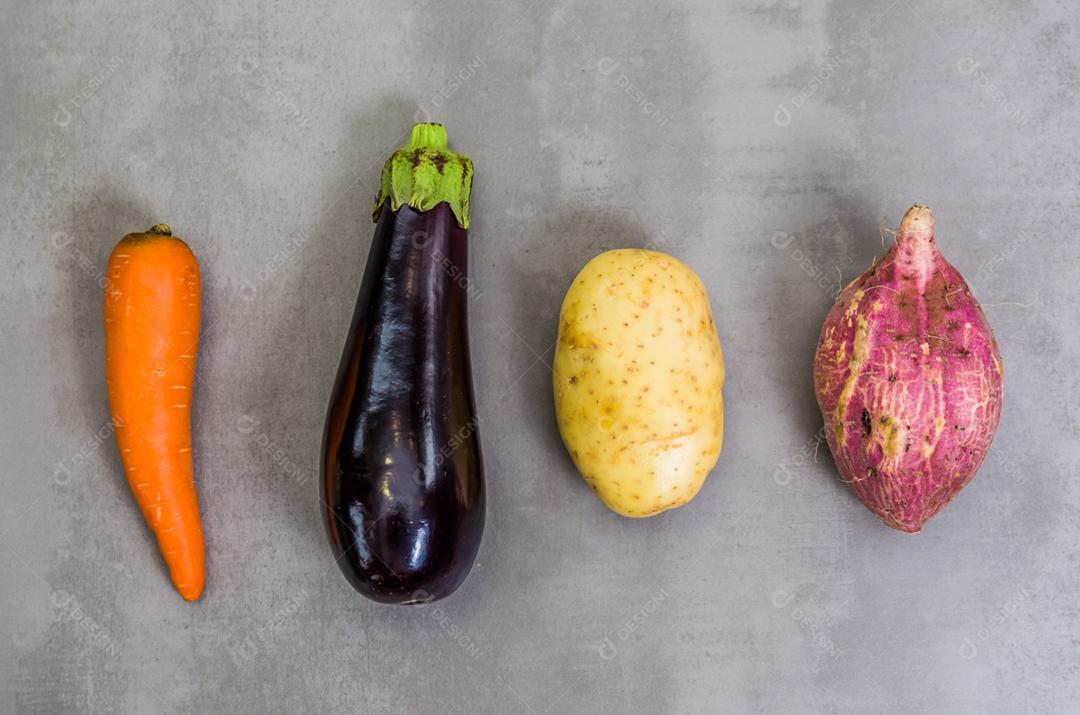 Grande conceito de alimentação saudável, legumes, batata, batata doce, cenoura, berinjela. Fundo cinza, concreto polido.