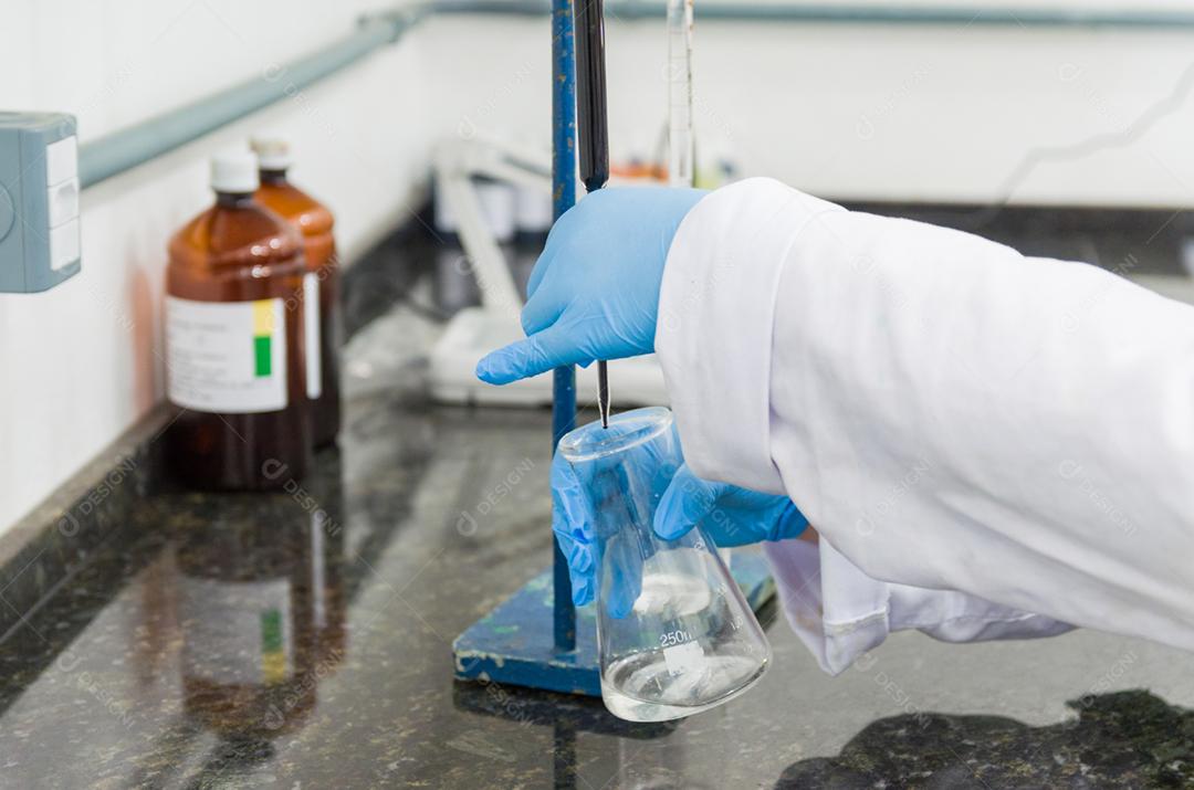 Mãos de mulher realizando teste de titulação no controle de qualidade química.