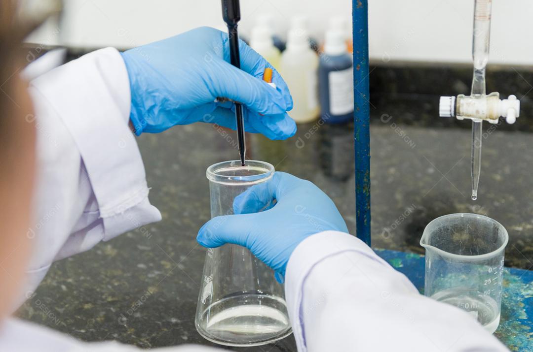 Mãos de mulher realizando teste de titulação no controle de qualidade química.