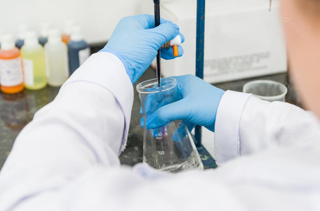 Mãos de mulher realizando teste de titulação no controle de qualidade química.