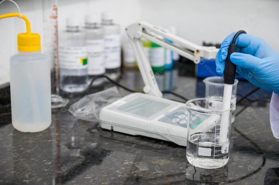 Mãos de mulher realizando teste de pH no instrumento eletrônico do medidor de pH para controle de qualidade na indústria química.
