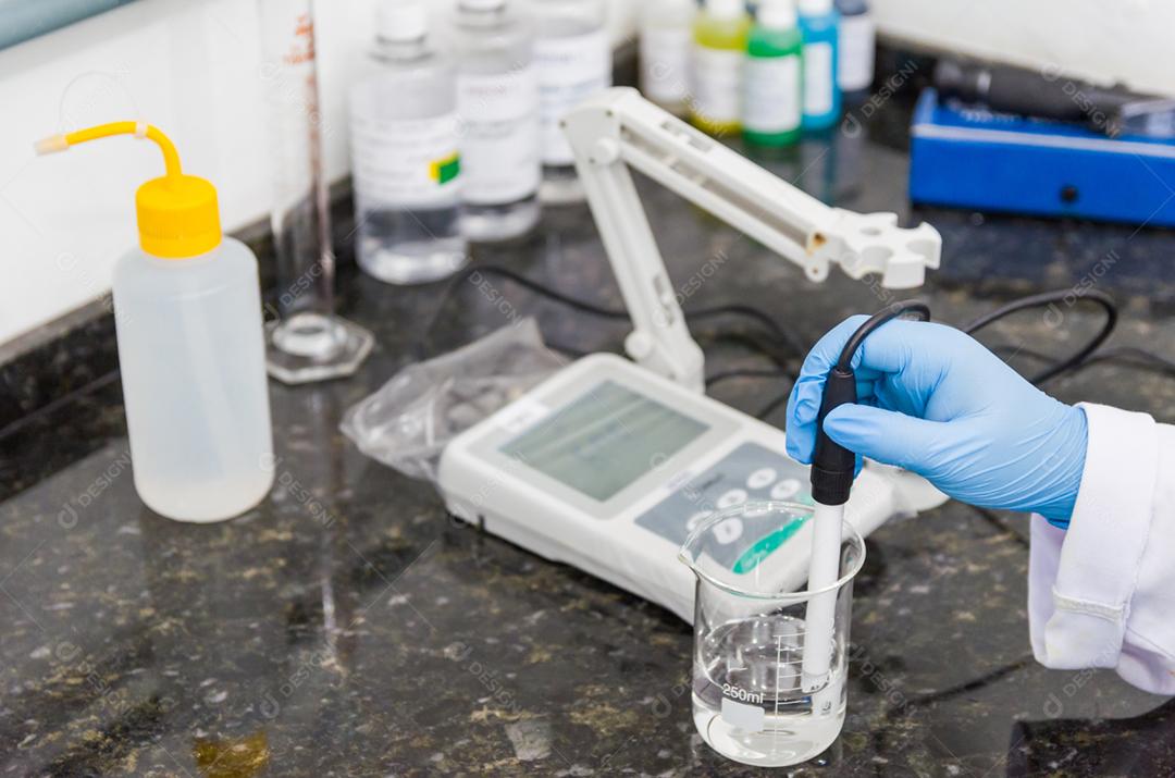 Mãos de mulher realizando teste de pH no instrumento eletrônico do medidor de pH para controle de qualidade na indústria química.