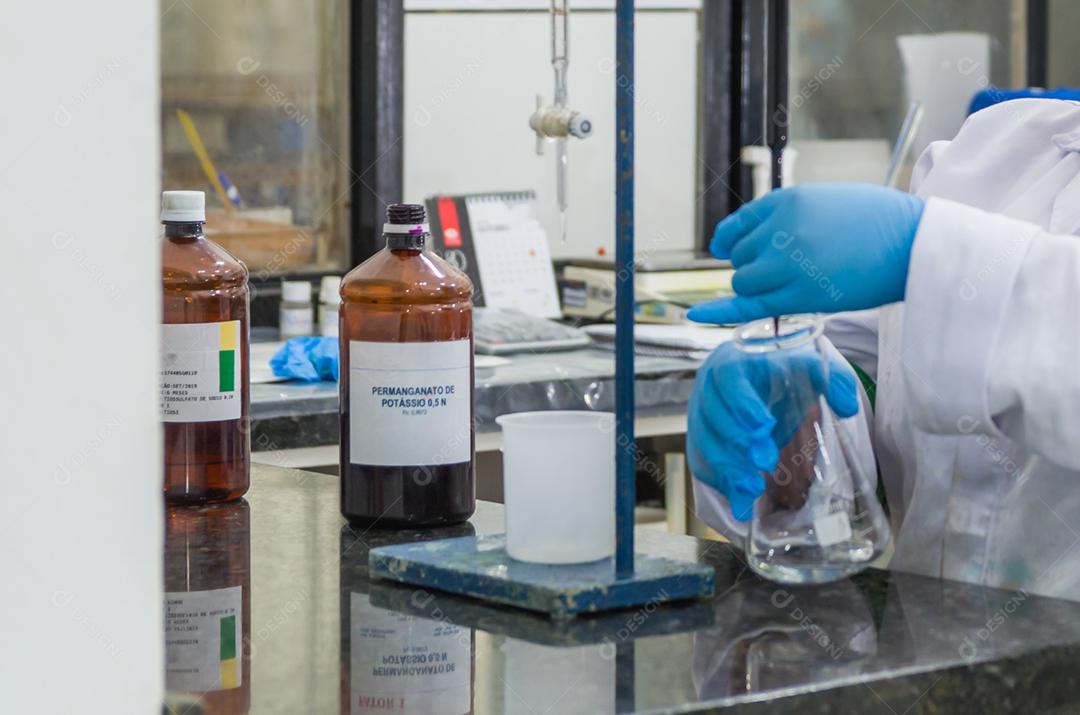 Mãos de mulher realizando teste de pH no instrumento eletrônico do medidor de pH para controle de qualidade na indústria química.