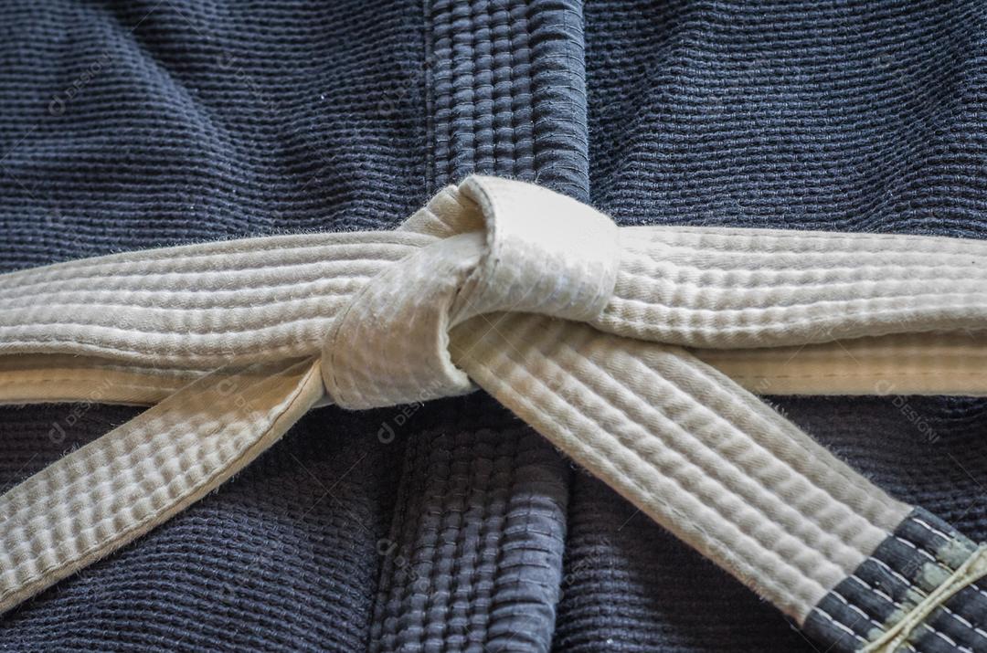 Faixa branca de Brazilian Jiu-Jitsu com quatro graus, em cima do kimono.