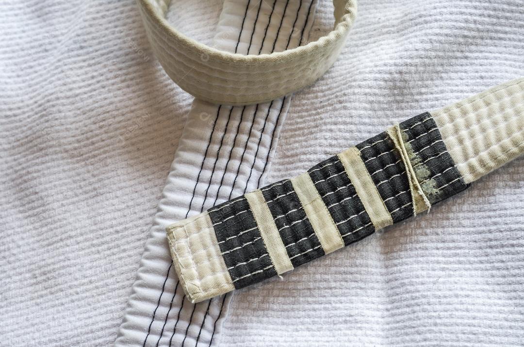 Faixa branca de Brazilian Jiu-Jitsu com quatro graus, em cima do kimono.