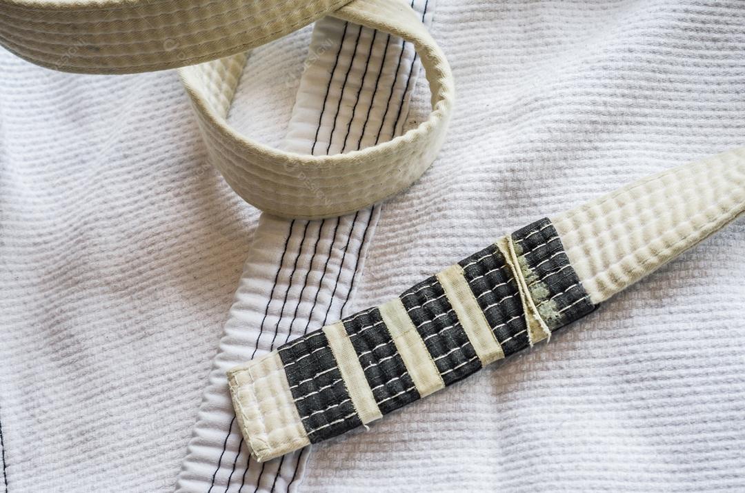 Faixa branca de Brazilian Jiu-Jitsu com quatro graus, em cima do kimono.