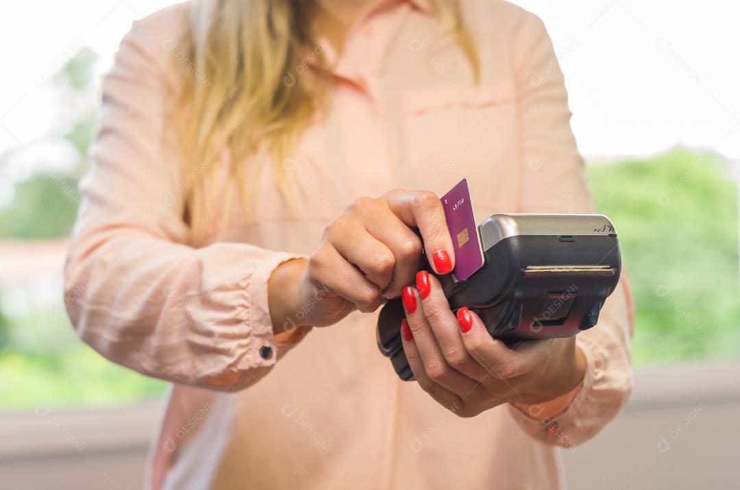 Grande conceito de pagamento com cartão de crédito, jovem caucasiana fazendo pagamento com cartão de crédito na máquina.