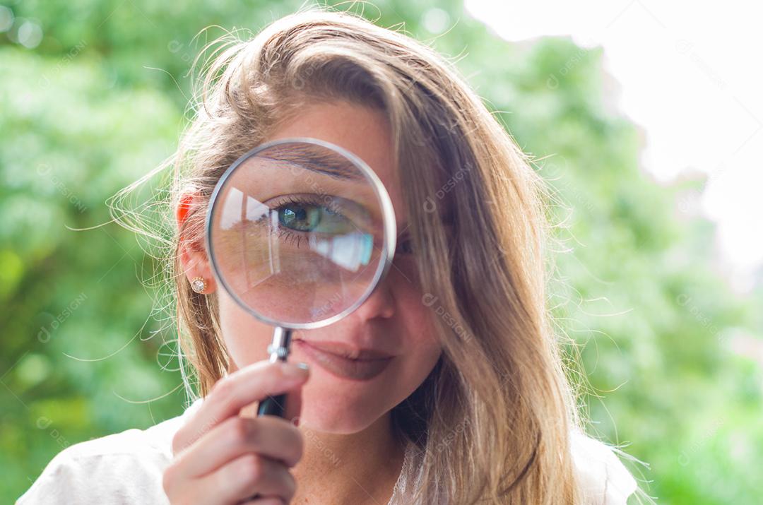 Grande conceito de pesquisa e investigação, jovem loira olhando através da lupa.
